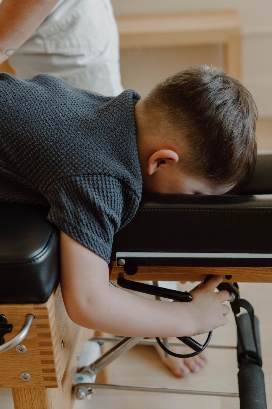 A young boy resting face down on the adjusting table