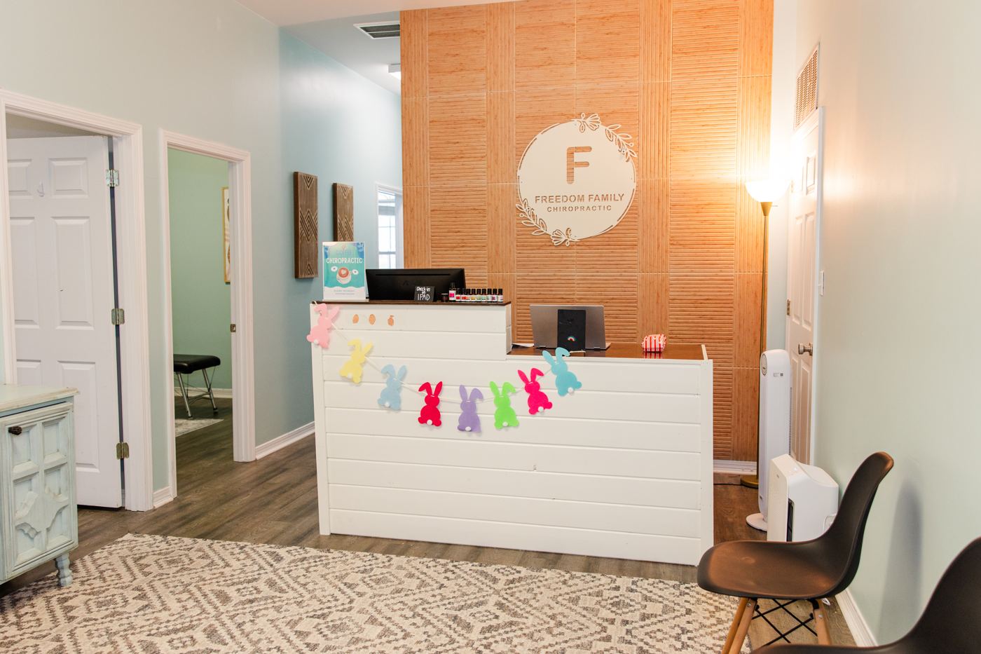 The Freedom Family Chiropractic front desk with the logo on a warm wood wall