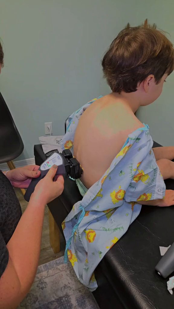 Dr. Kayla running a gentle INSiGHT EMG scan along a young boy's spine