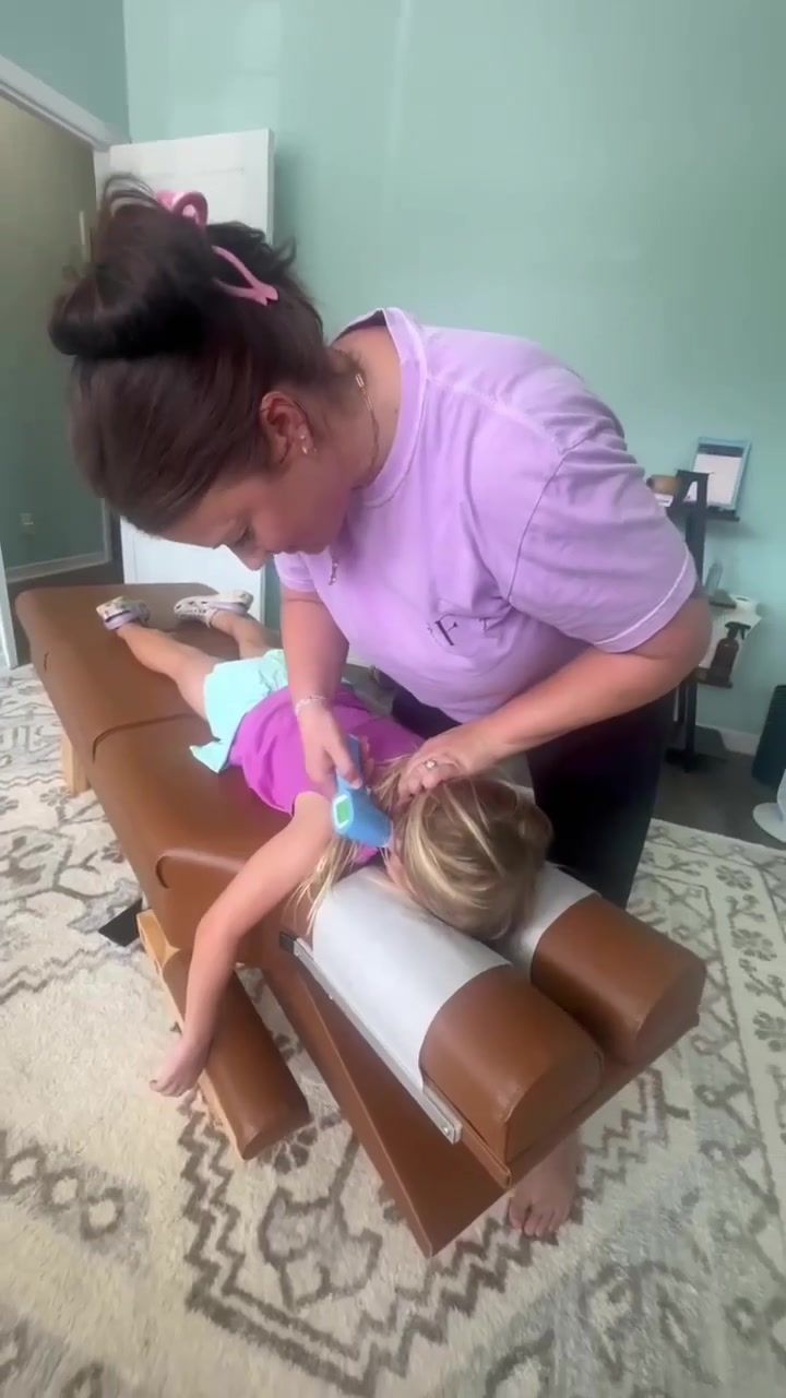 Dr. Kayla running a Neuro Thermal scan on a young girl lying face down